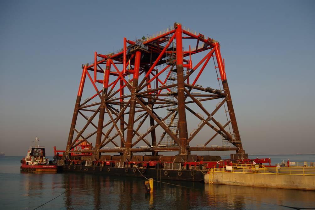 Steel jacket structure on a barge beside a quay.